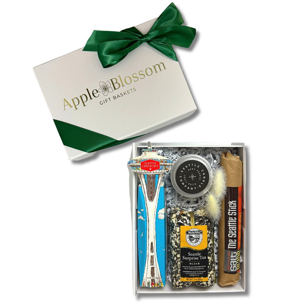 the seattle gift box features a space needle truffle gift box, seattle sprprise loose tea, seattle candle company coffee candle and the seattle stick salami. The gift come is a white soft touch gift box with a green ribbon