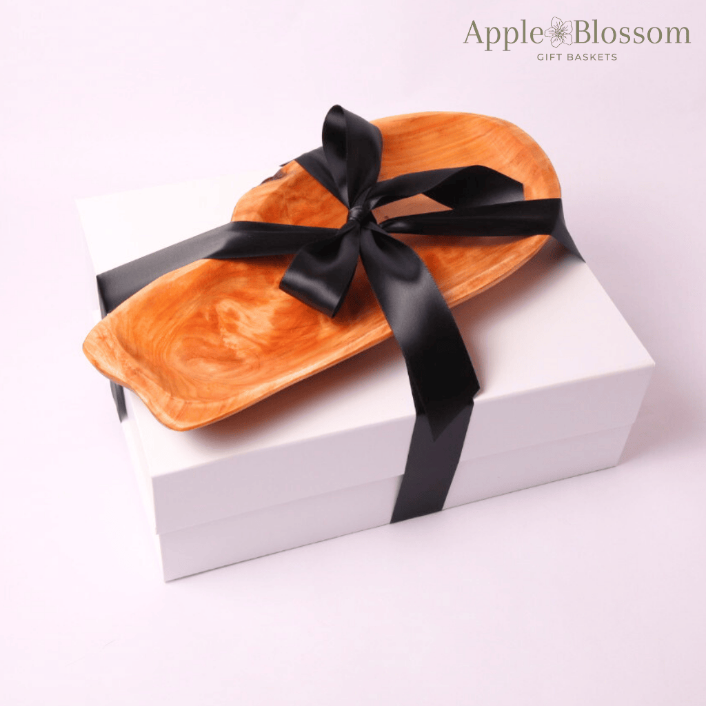 Closed luxury gift box wrapped in a sleek black satin bow and hand carved wooden serving tray made in WA, presenting a beautifully curated home essentials set—an exquisite gift for new homeowners.