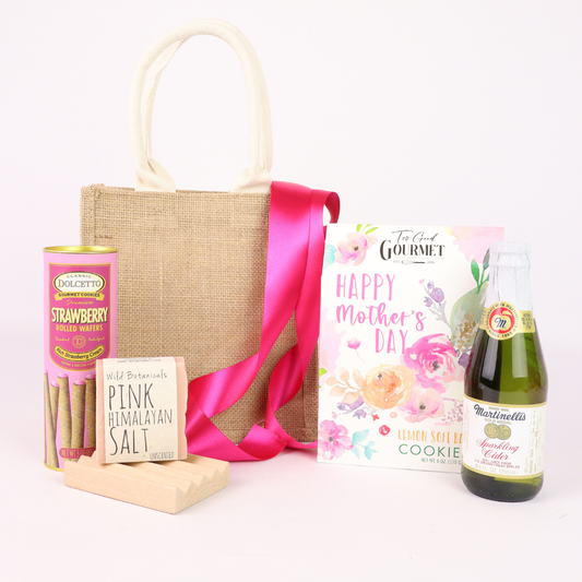 Mother’s Day gift basket contents with lemon cookie, strawberry wafers, sparkling cider, soap, wooden dish, and burlap tote
