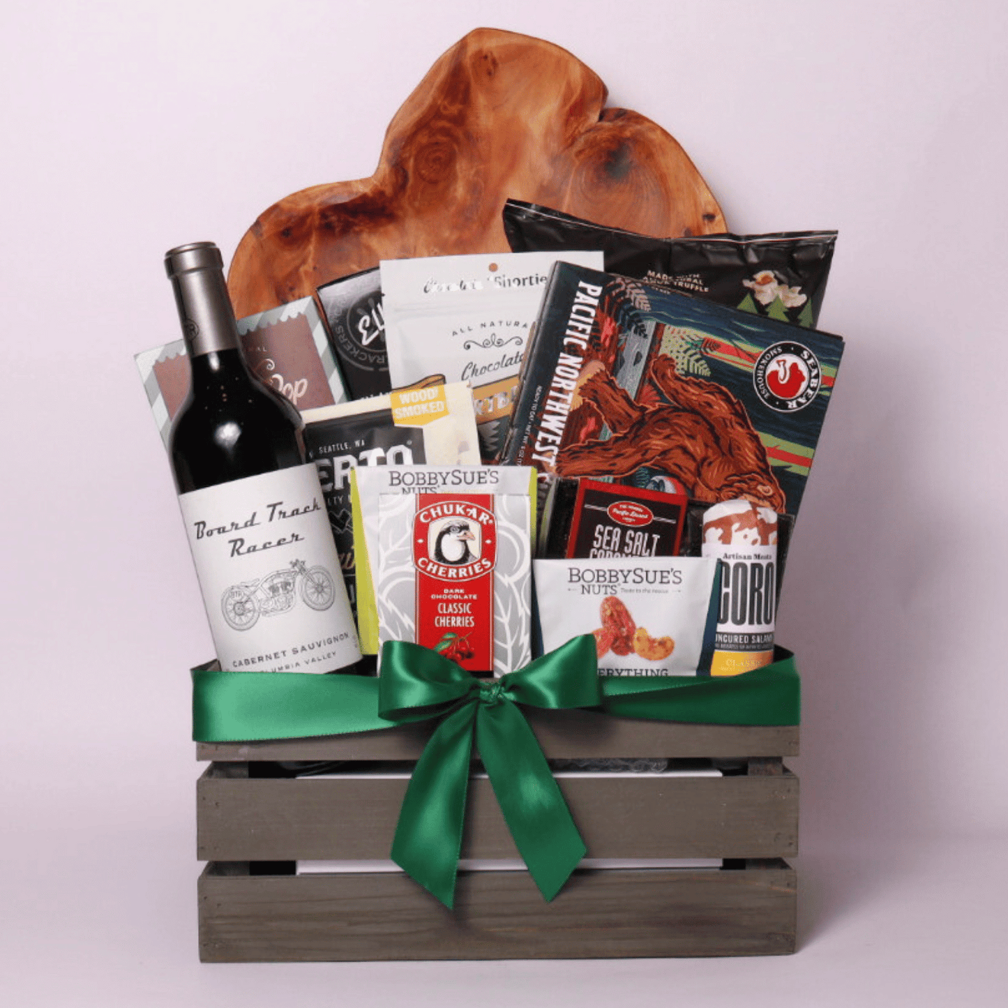 Best of the Northwest gift basket featuring artisan smoked salmon, Chocolate Cherries, gourmet nuts, handcrafted chocolate, popcorn, crackers, Florentina spritz, and other Pacific Northwest treats in a rustic wooden crate with a green satin bow.