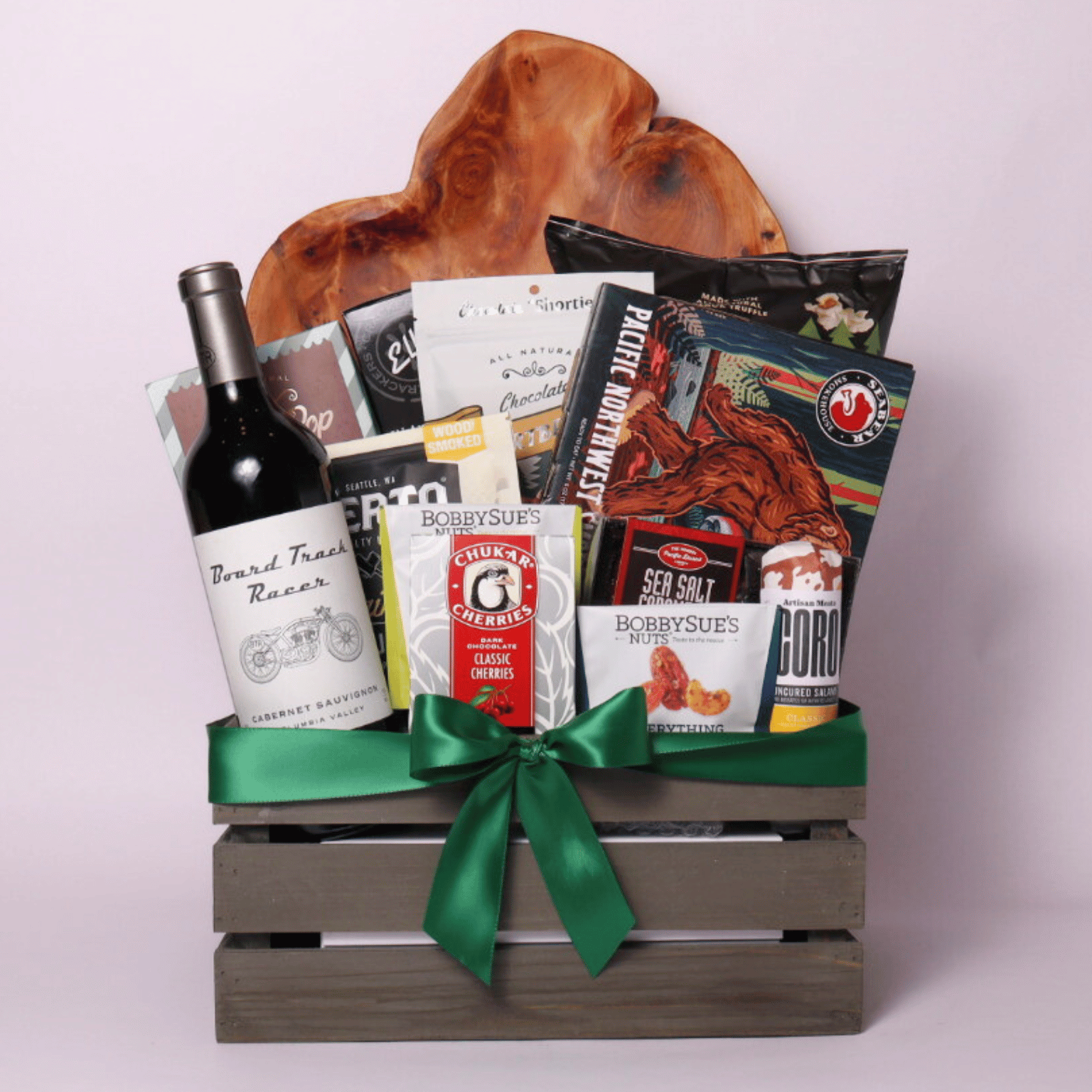 Best of the Northwest gift basket featuring artisan smoked salmon, Chocolate Cherries, gourmet nuts, handcrafted chocolate, popcorn, crackers, Florentina spritz, and other Pacific Northwest treats in a rustic wooden crate with a green satin bow.