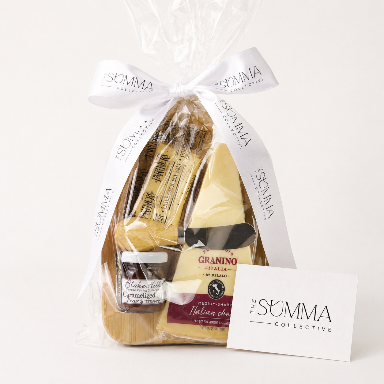 Luxury artisan cheese and charcuterie gift set with branded white ribbon and custom The Summa Collective message card, featuring gourmet crackers, salami, smoked gouda cheese spread, roasted garlic spread, mixed nuts, and premium snacks in elegant corporate gift packaging.