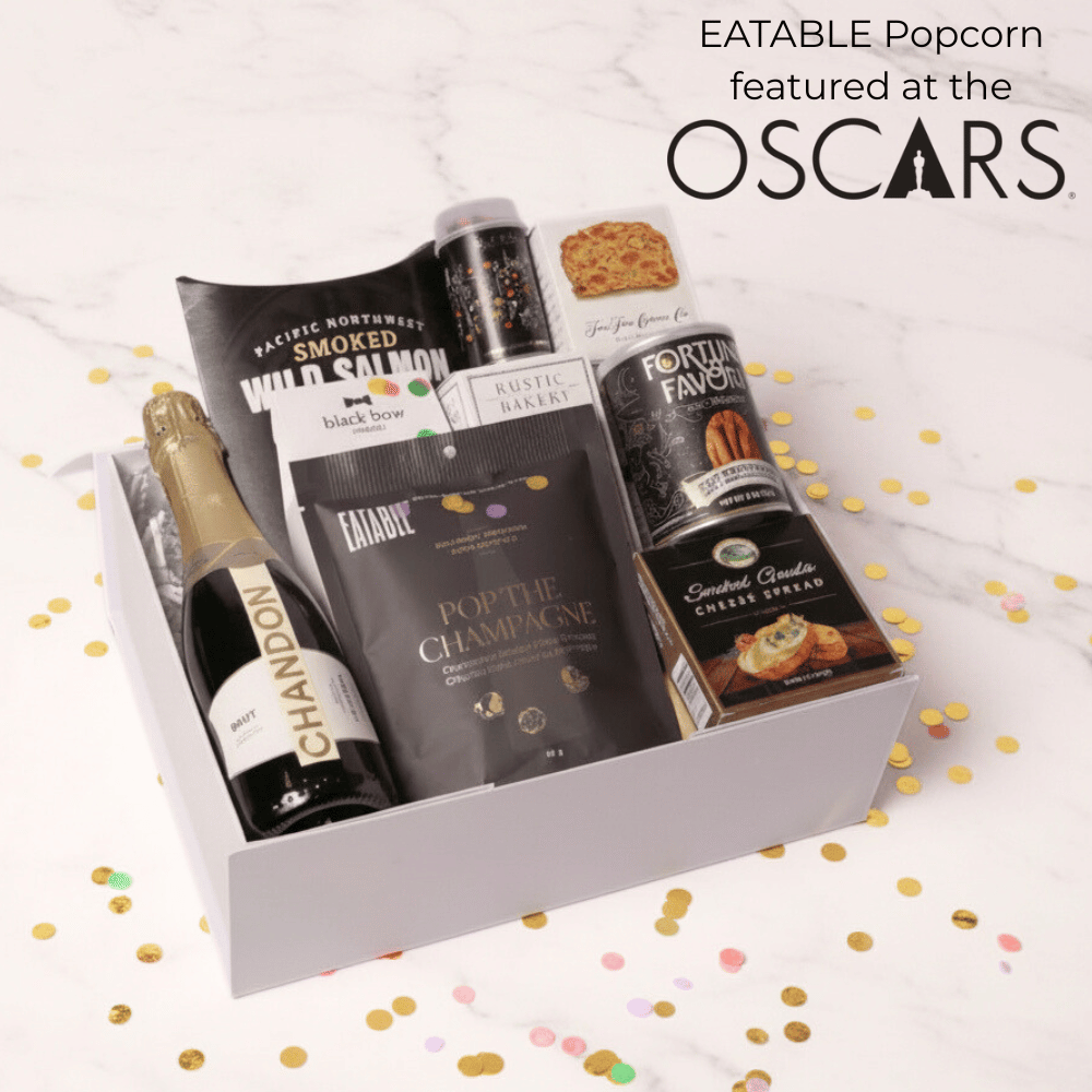 Gift box with Eatable Popcorn and other snacks on a white background with confetti.
