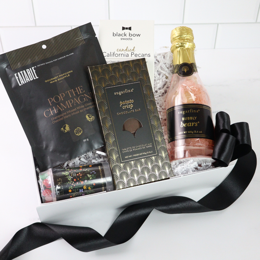 Luxury celebration gift box featuring champagne-infused popcorn, Sugarfina treats, a confetti popper, and a mini bottle of bubbly gummy bears.