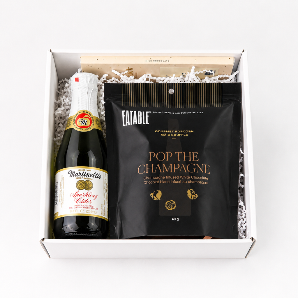 Open client anniversary gift box with sparkling cider, champagne popcorn and artisan chocolate