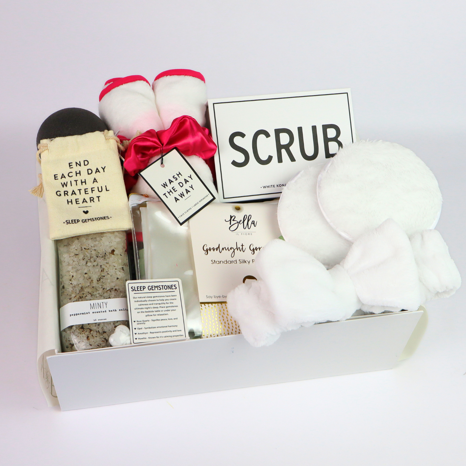 Day At The Spa Gift Basket Spa gift box filled with peppermint bath salts, pink scrunchie and cloth set, white headband, cleansing pads, konjac sponge, and SCRUB sponge—presented in a white box.