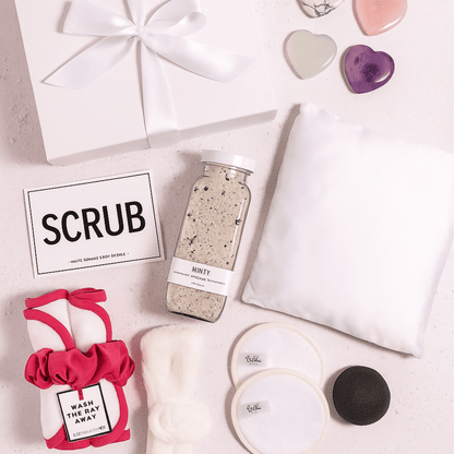 Day At The Spa Gift Basket Day At The Spa Gift Basket Day At The Spa Gift Basket Flat lay of spa gift contents featuring a pink scrunchie, SCRUB sponge card, bath salts, headband, and face cloths—highlighting customer review.