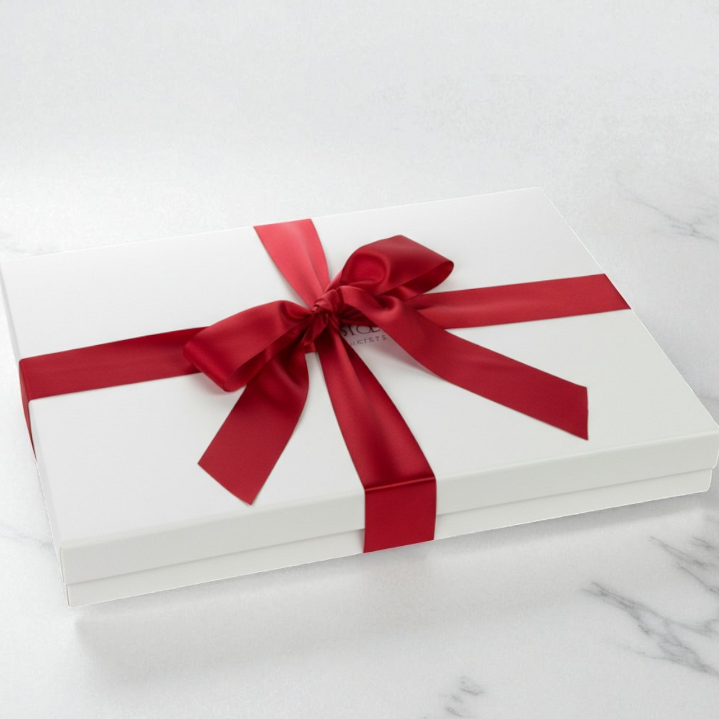 large White gift box with a red ribbon on a marble surface