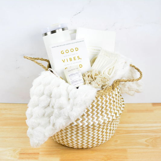 Executive Relaxation Gift Basket with cozy blanket, tumbler, book, tea, socks, and notebook in neutral woven basket