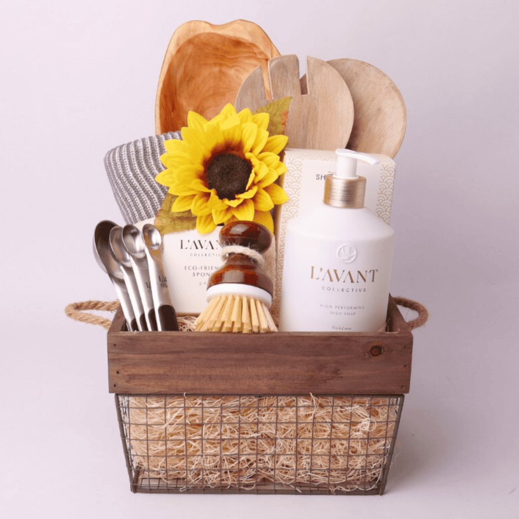 For the Kitchen Gift Basket – A beautifully curated kitchen gift basket featuring L’AVANT dish soap, eco-friendly sponges, a salad serving set, a hand-carved wooden platter, and more, elegantly arranged in a rustic wire and wood basket. Seattle housewarming  gift baskets