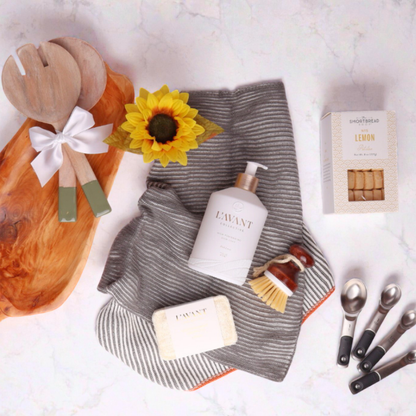 Flat Lay of Kitchen Gift Basket Items – A top-down view showcasing the elegant kitchen essentials, including handcrafted wooden utensils, premium dish soap, and eco-friendly cleaning tools, perfect for gifting.