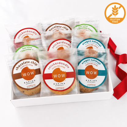 A white gift box containing six individually wrapped gluten-free cookies from Snickerdoodle Baking Company, each with a colorful round label. The cookies include chocolate chip, vanilla, key lime chocolate chip, soy lime chocolate chip, and Oregon oatmeal.