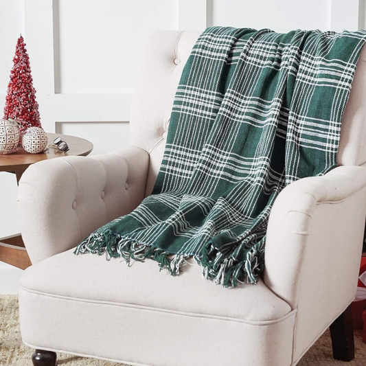Green checked plaid throw blanket draped over armchair, luxury PNW gift basket accessory for Christmas gifts, birthdays, or cozy home décor.