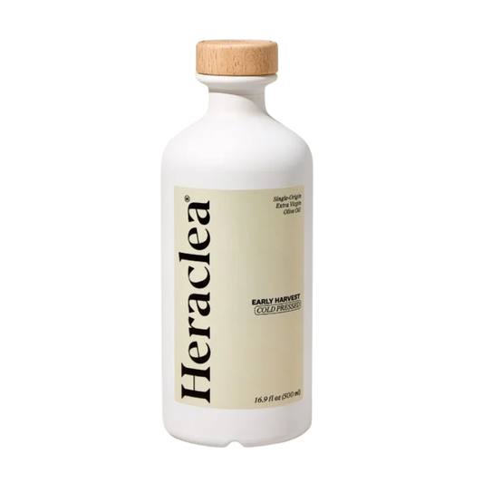 A white bottle of Heraclea Extra Virgin Cold Pressed Olive Oil with a light wood cap and a beige label, shown on a plain white background.
