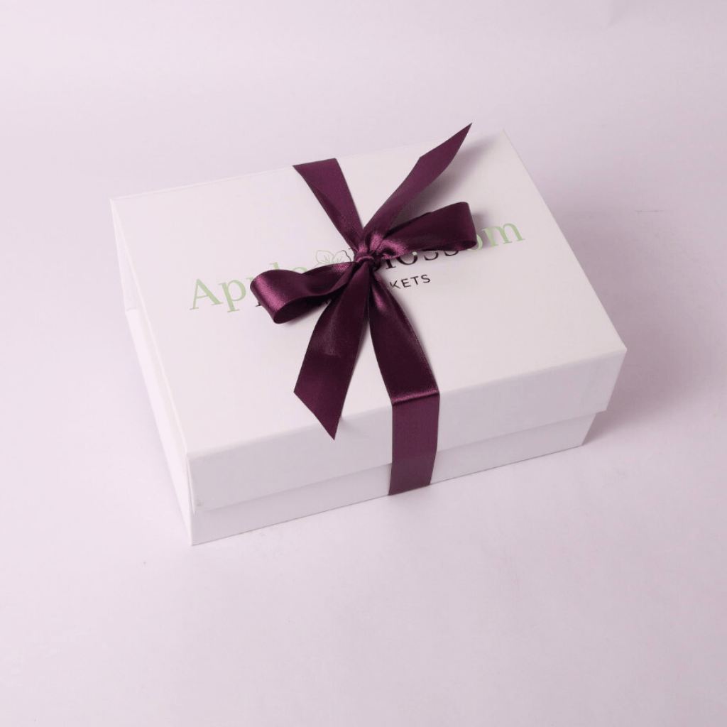 Signature white luxe gift box of the Washington Huckleberry Breakfast Gift Set in Gift Box – A delicious huckleberry-themed treat box filled with gourmet goodies, ideal for housewarmings, corporate gifts, and thinking-of-you surprises.  Wrapped with a purple satin bow