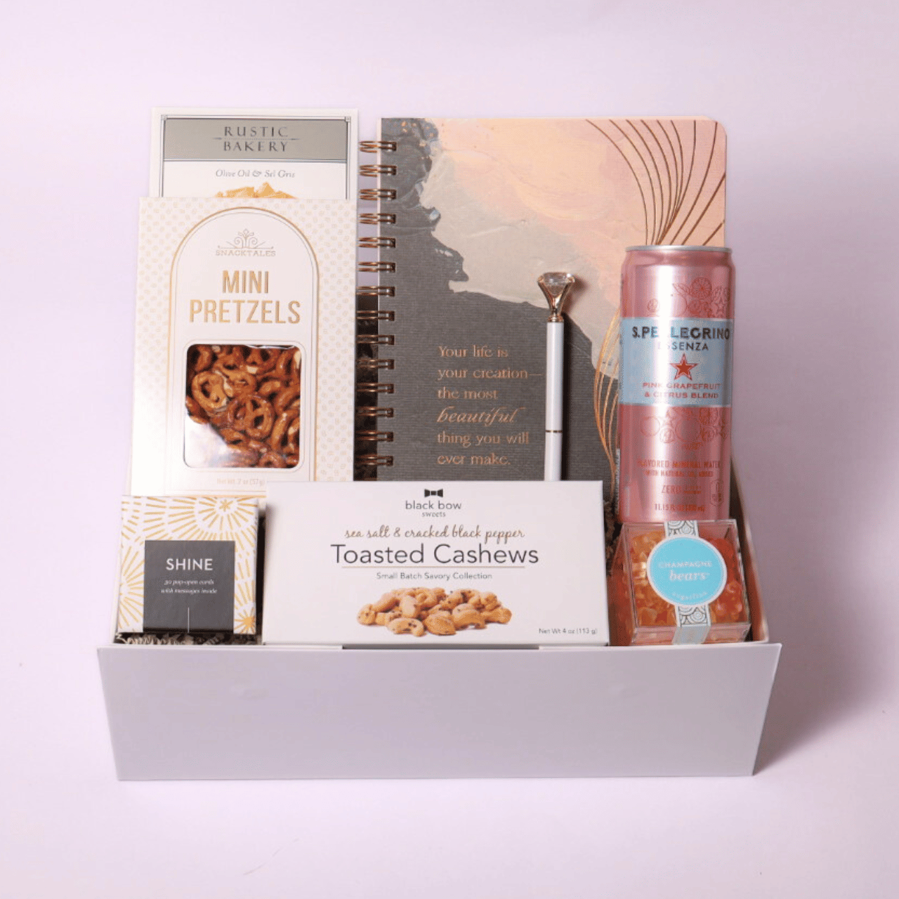 Uplifting gift box with a motivational notebook, diamond pen, champagne gummy bears, and Shine Pop Open Cards for daily inspiration and positivity.