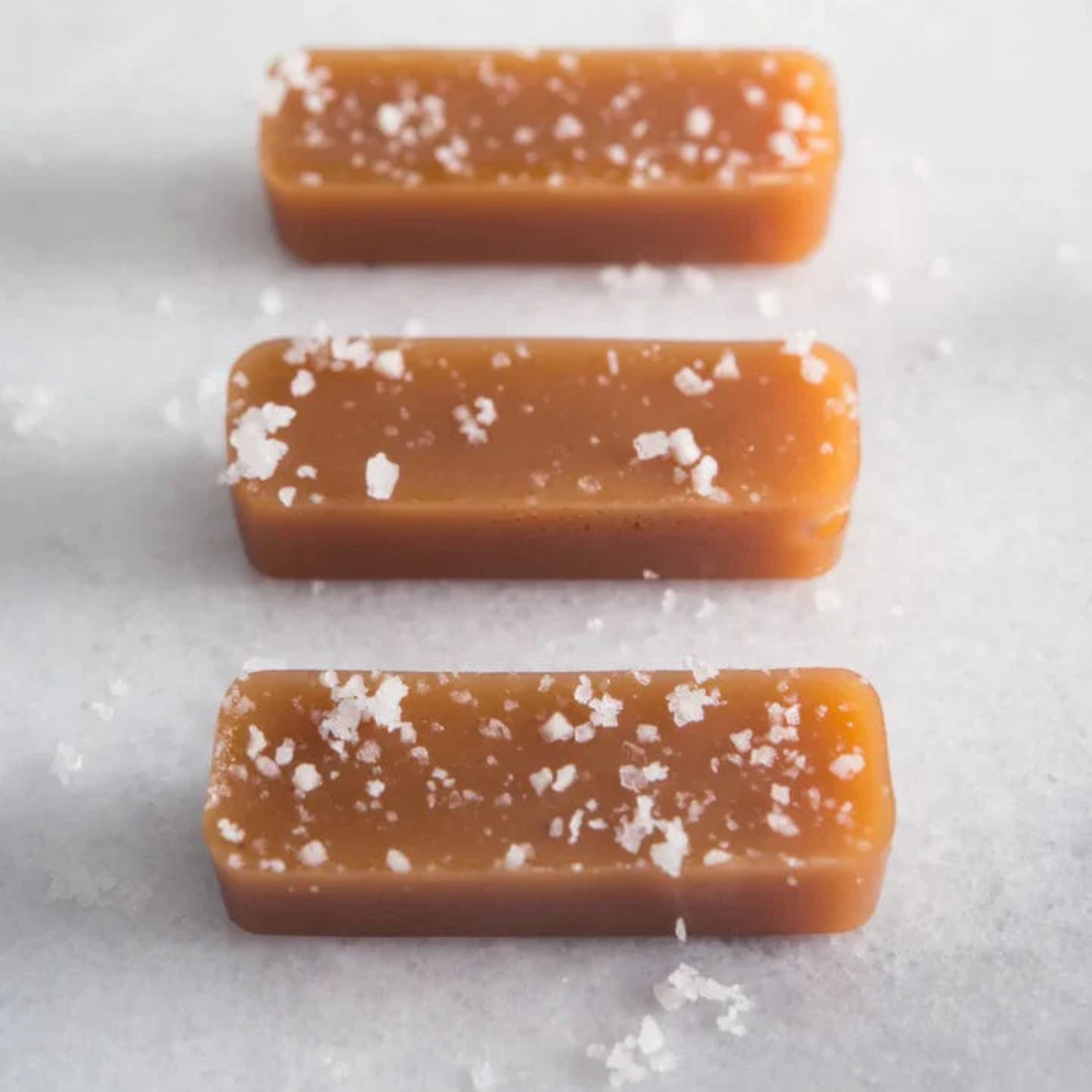 Three caramel bars with sea salt on a white background