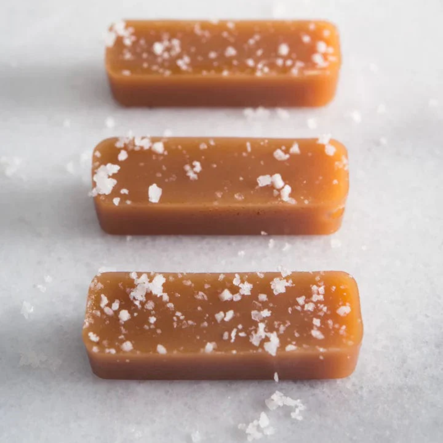 Three caramel bars with sea salt on a white background
