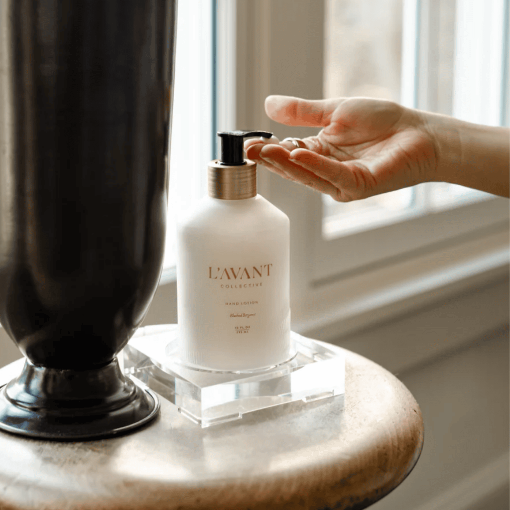 A close-up of L'AVANT Collective Blushed Bergamot Hand Lotion in an elegant glass dispenser, packed with nourishing, plant-based ingredients for a spa-like experience