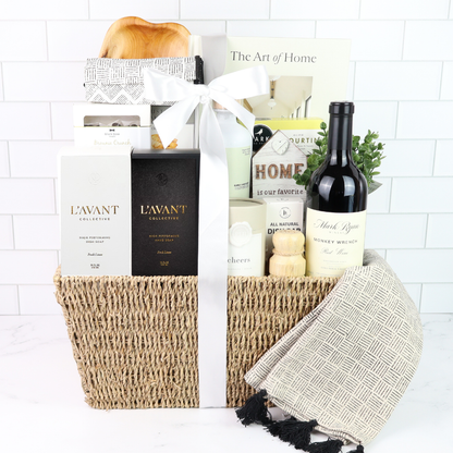 Luxury housewarming gift basket with wine, washington made hand soap, lotion, cutting board, crackers, almonds, and a beautiful book, displayed in a woven basket with a sage satin bow.