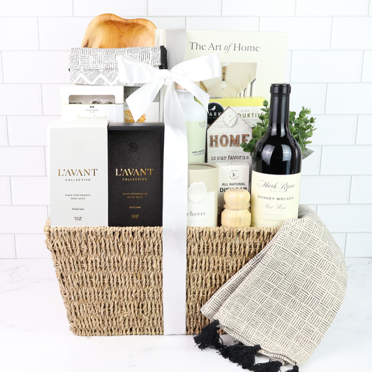 Luxury housewarming gift basket with wine, washington made hand soap, lotion, cutting board, crackers, almonds, and a beautiful book, displayed in a woven basket with a sage satin bow.