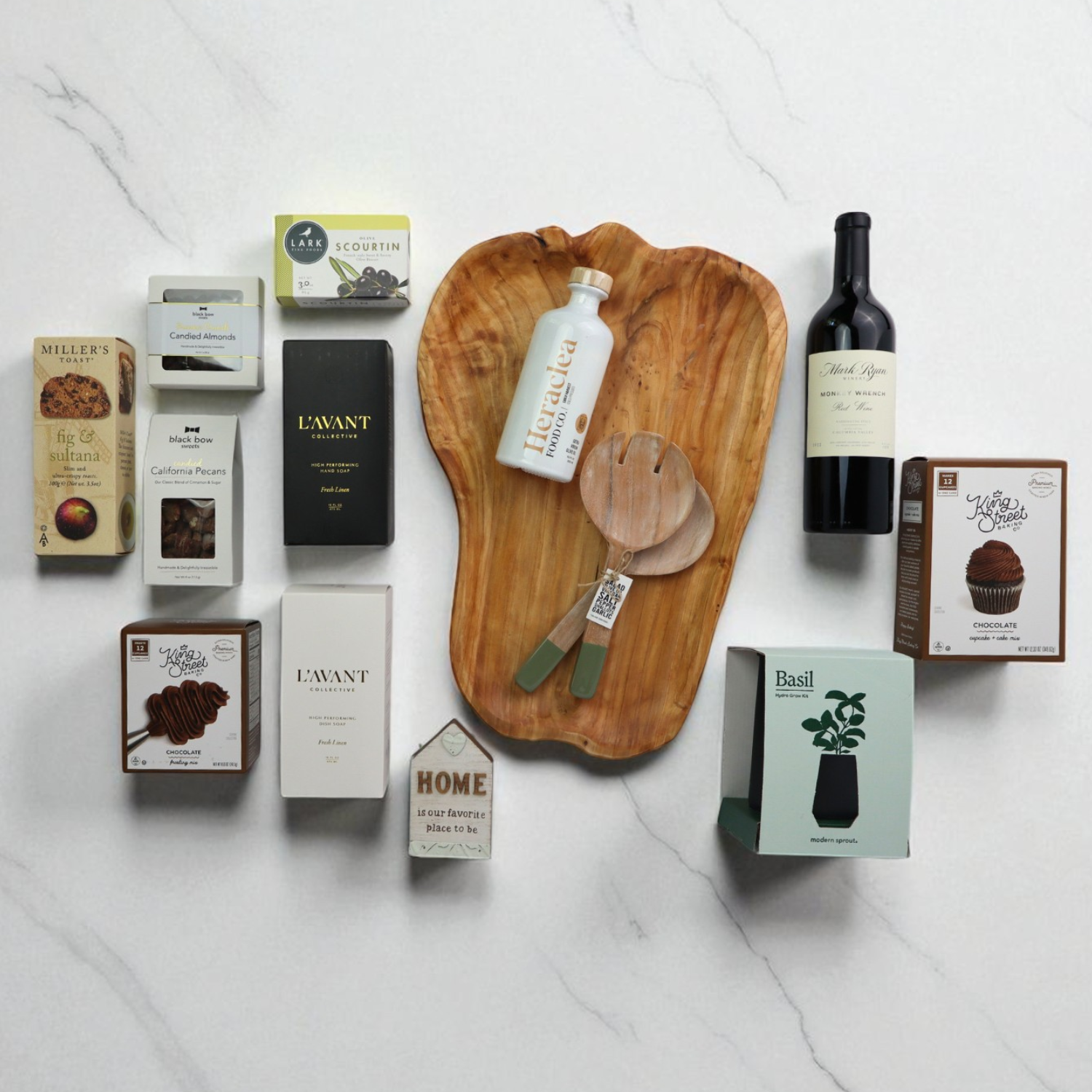 Collection of items including a wooden cutting board, wine bottle, and various boxes on a white marble surface.