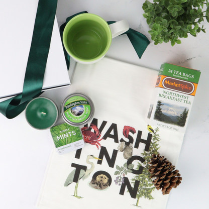 Gift box featuring locally crafted Pacific Northwest treats, including MarketSpice tea, Seattle Chocolate mint bar, soy candle, churro cookies, and a ceramic teacup. Perfect for tea lovers and relaxing break times.