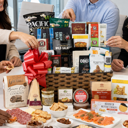 Large gourmet office gift basket being shared by coworkers with smoked salmon, cheese, crackers, salami, chocolates, cookies, nuts, spreads, and Pacific Northwest snacks.