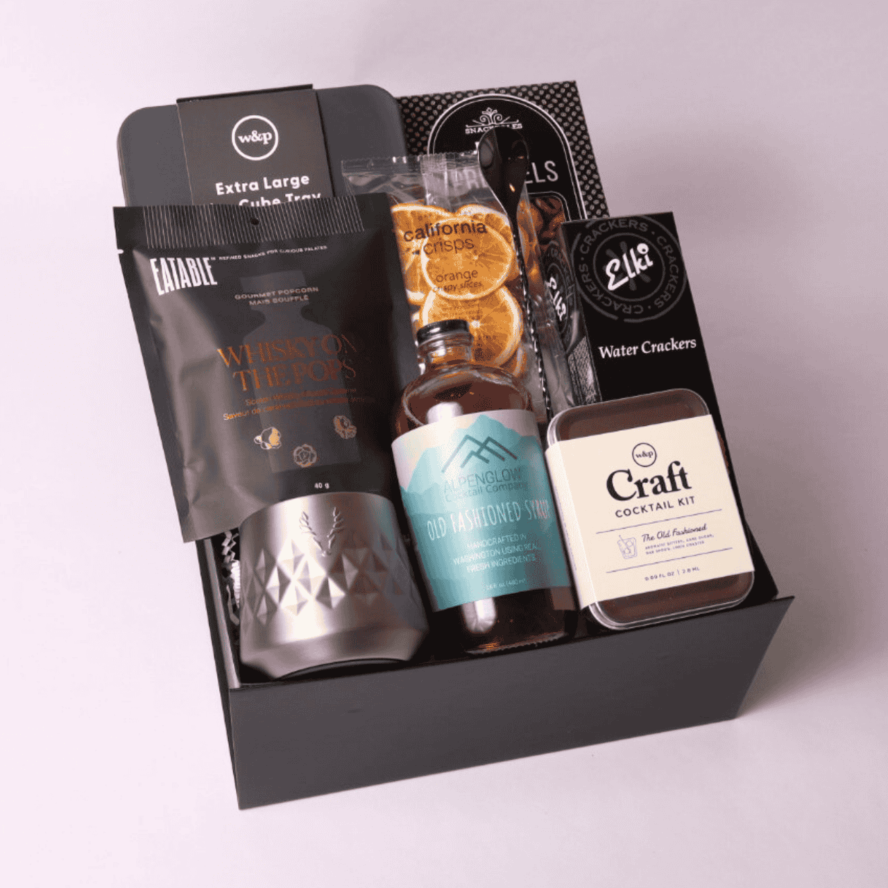 Luxury old fashioned-themed gift box filled with premium items: stainless whiskey tumbler, craft cocktail kit, whiskey popcorn, ice cube mold, and more—perfect for bourbon enthusiasts.