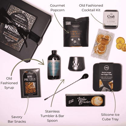 Flat lay of the old fashioned themed gift box contents, featuring Alpenglow Old Fashioned Cocktail Syrup handcrafted in Washington, alongside infused popcorn, a tumbler, ice mold, cocktail kit, and more.