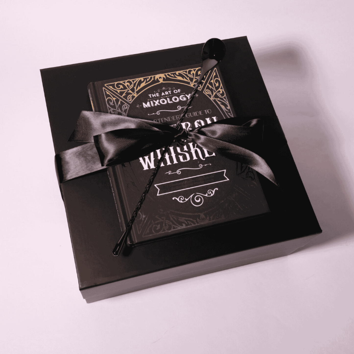 Luxury old fashioned gift box wrapped with a black satin bow, featuring the cocktail recipe book and bar spoon elegantly displayed on top, perfect for gifting.