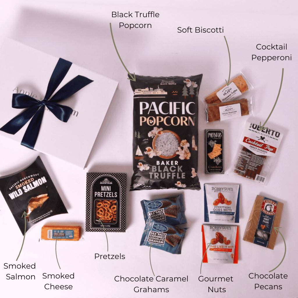 Flat lay of a gourmet snack gift box featuring Pacific Northwest popcorn, smoked pretzels, chocolate sea salt caramel grahams, Chukar Cherries, nuts, and more. A perfect assortment for gifting.
