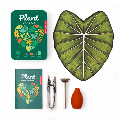 Plant care kit with leaf-shaped container, care booklet, trowel, and watering can on a white background