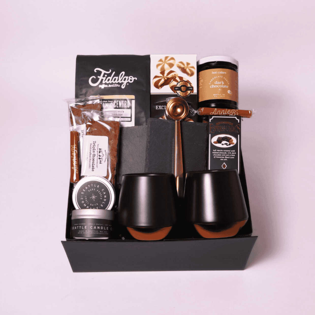 Gourmet coffee gift basket with high-quality Fidalgo coffee, double-walled mugs, cream-filled cookies, biscotti, and slate coasters, arranged in a signature black box.