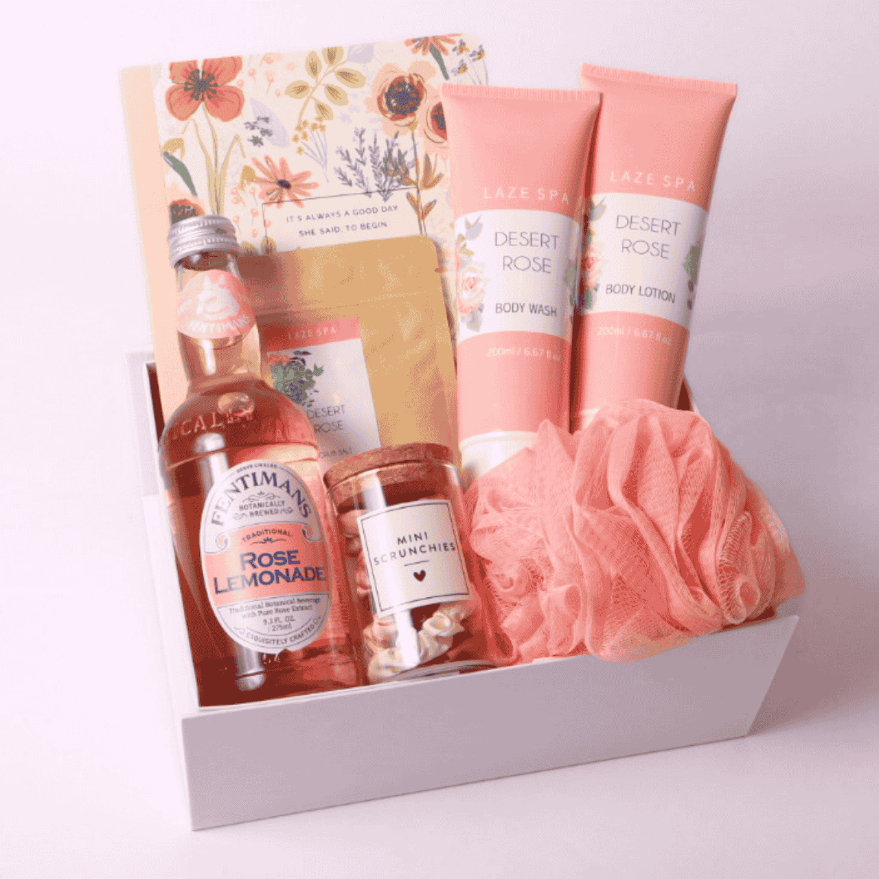 Rose Garden Gift Box with spa and self-care essentials – Includes Fentimans Rose Lemonade, Laze Spa Desert Rose Body Wash and Lotion, a soft pink bath pouf, rose-infused loose tea, a floral notebook, and mini scrunchies in a white gift box. Perfect for relaxation, sympathy, or self-care gifts.