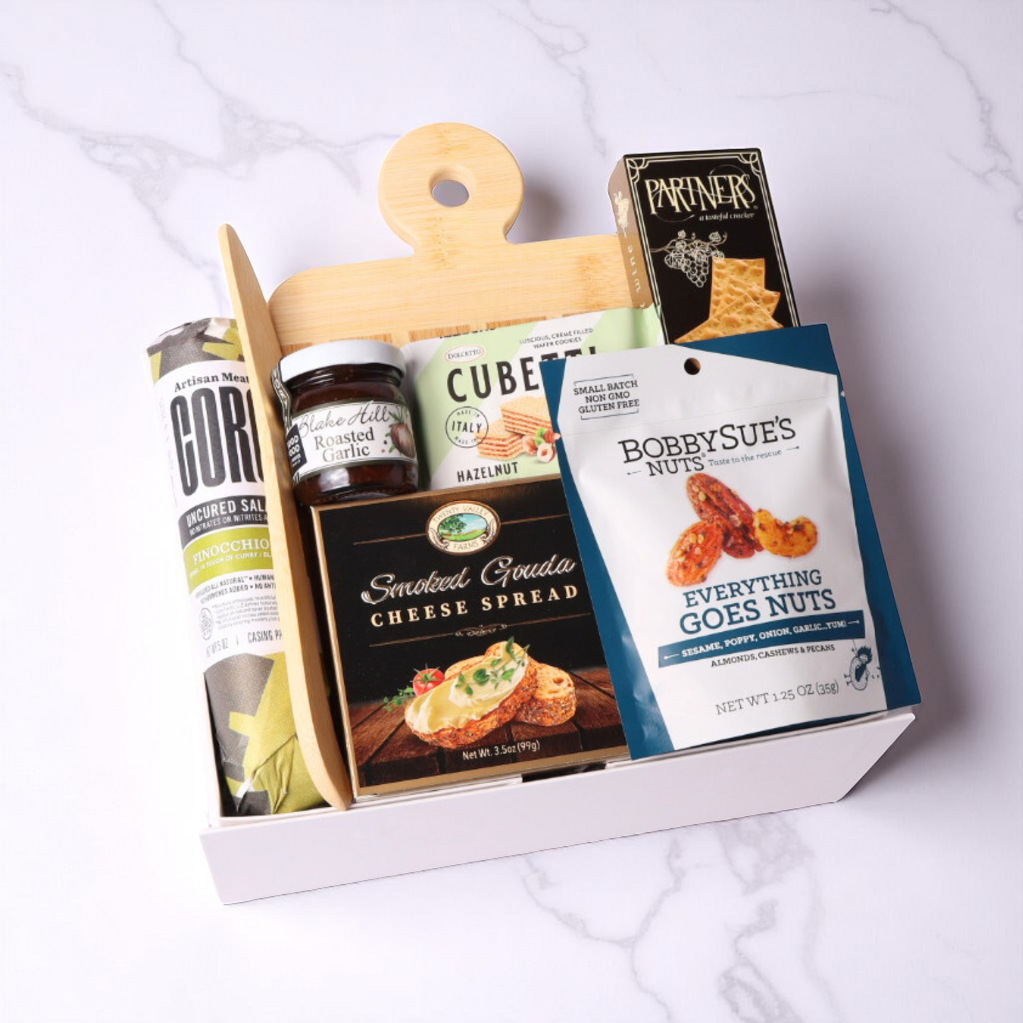 Simply Savory Gift Box featuring a bamboo paddle board, spreading knife, gourmet crackers, salami made in WA, cheese spread, savory jam, nuts, and hazelnut wafer cookies, perfect for hostess or housewarming gifts.