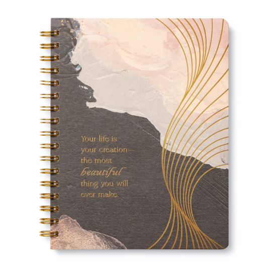 Notebook with artistic design and motivational quote on a white background