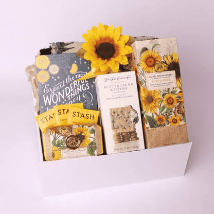 “Sunflower-themed gift box from a Seattle small business featuring cozy throw, tea, journal, soap, diffuser, and gourmet crackers—perfect for thoughtful gifting.”