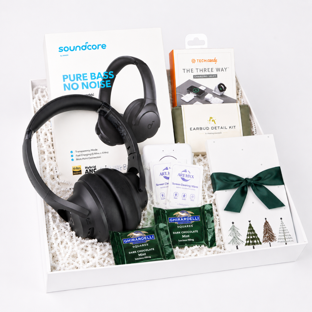 A curated gift box set containing a pair of black Soundcare over-ear headphones, a Soundcore Pure Bass No Noise card, a Nintendo earbud detail kit box, a packet of Ghirardelli chocolate, and a white card tied with a dark green ribbon.