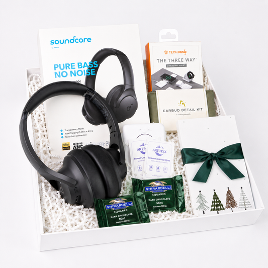 A curated gift box set containing a pair of black Soundcare over-ear headphones, a Soundcore Pure Bass No Noise card, a Nintendo earbud detail kit box, a packet of Ghirardelli chocolate, and a white card tied with a dark green ribbon.
