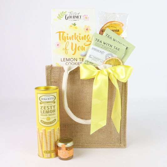 Thinking of You Lemon Tea Gift Set with lemon cookies, tea, dried orange slices, honey, lemon wafer rolls, and jute tote