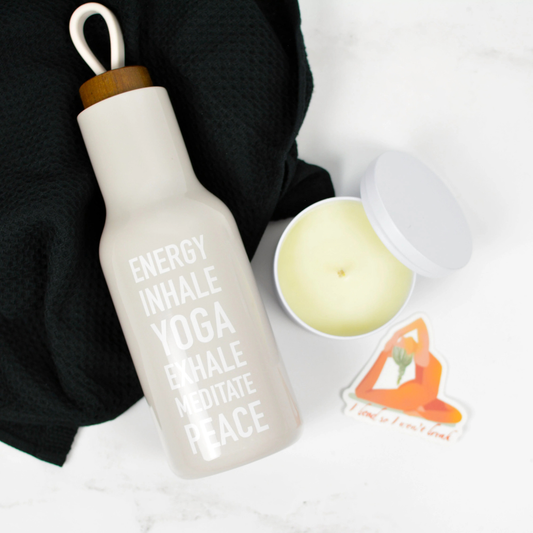 Yoga Lover gift set with reusable water bottle, black towel, candle, and yoga-themed sticker on neutral background
